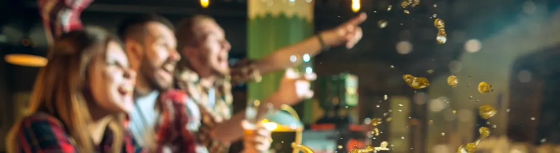 Freunde beim Biertrinken in einer Bar, freuen sich über ein Ereignis - das Event Add-On mit Kassensystem RFID von GastroSoft