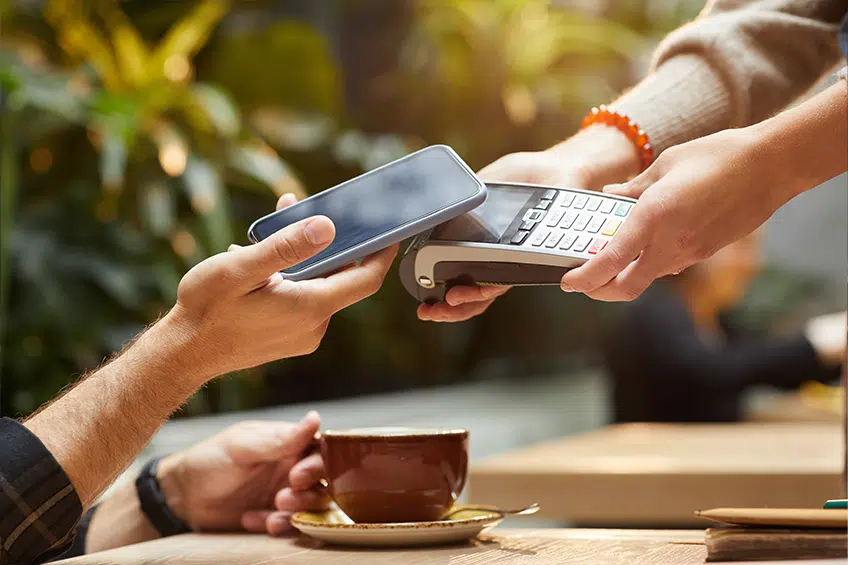 Close Up einer Zahlung mit dem Smartphone an einem mobilen Kartenterminal im Außenbereich eines Cafés - Digitalisierung Gastronomie, GastroSoft