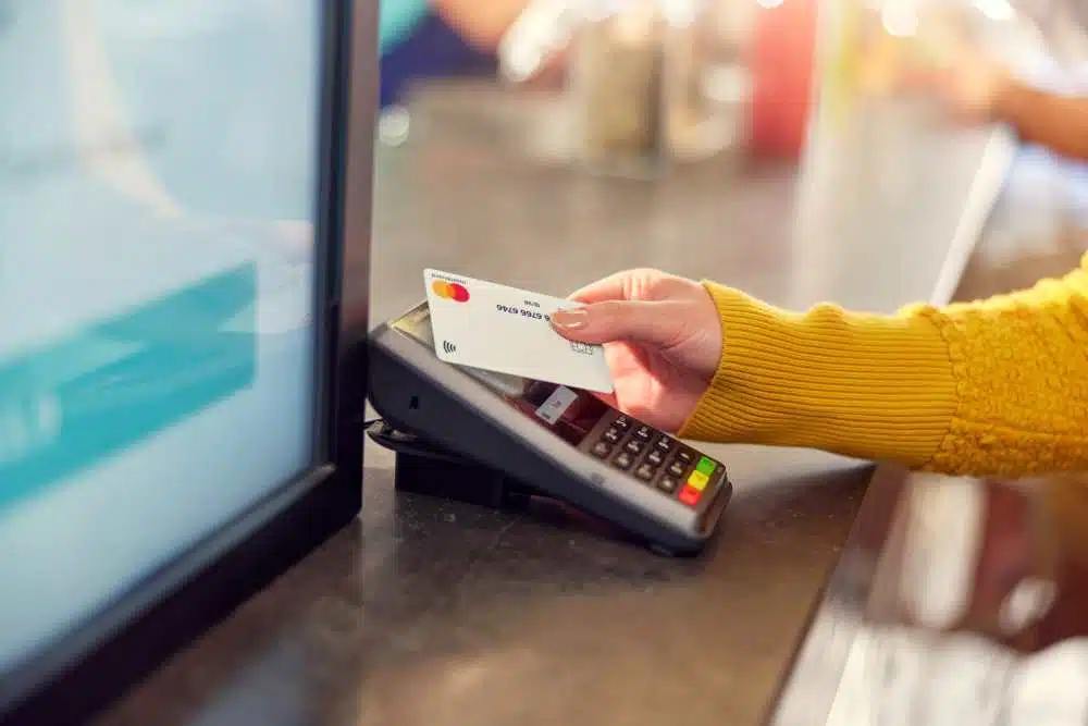 Frau hält ihre EC-Karte an ein Kartenlesegerät und bezahlt kontaktlos