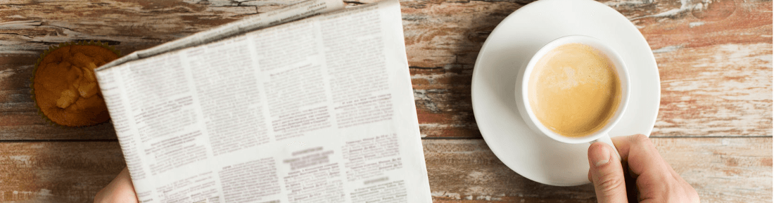 Person mit Zeitung und Kaffee am Holztisch - GastroSoft News, Blog und Newsletter über Kassenprodukte und Kassensysteme