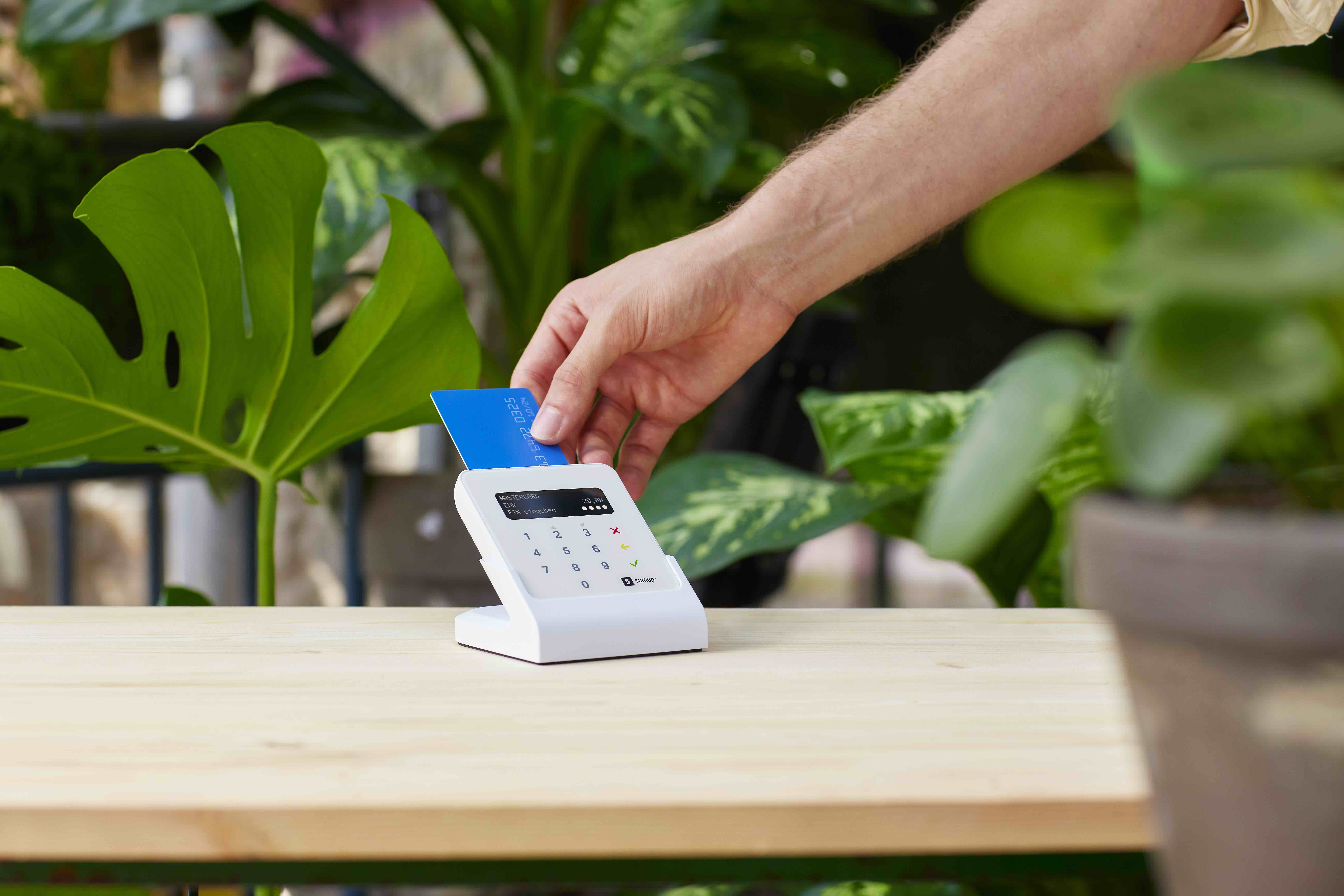 Kunde schiebt seine Bankkarte in das SumUp Air Kartenlesegerät ein, um seinen Einkauf im Blumenladen bargeldlos zu bezahlen